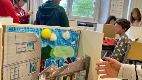 Photographie avec en premier plan une maquette et à l'arrière quelques élèves.
